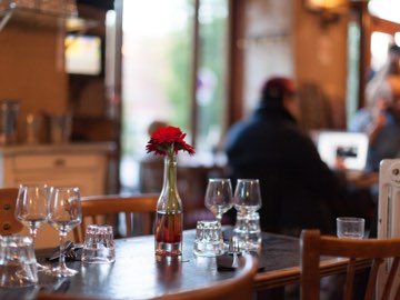 Une table dressée avec une fleur rouge dans une bouteille